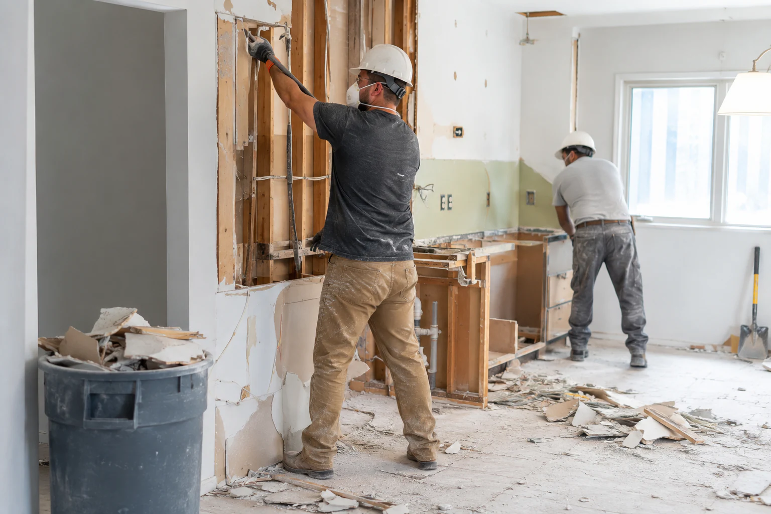 Workers performing light interior demolition inside a residential property